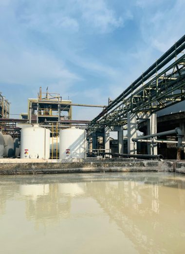 Aerial view of an industrial facility with large water tanks in Faisalabad, Pakistan under a clear sky.